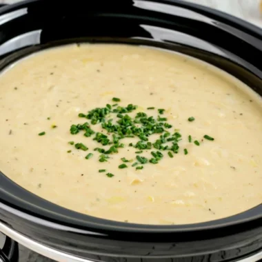 Bowl of slow cooker potato leek soup with fresh herbs and crusty bread