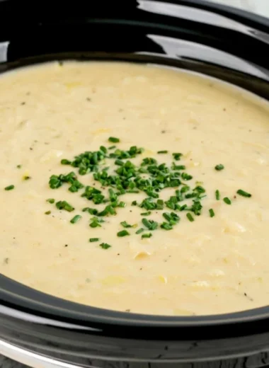 Bowl of slow cooker potato leek soup with fresh herbs and crusty bread